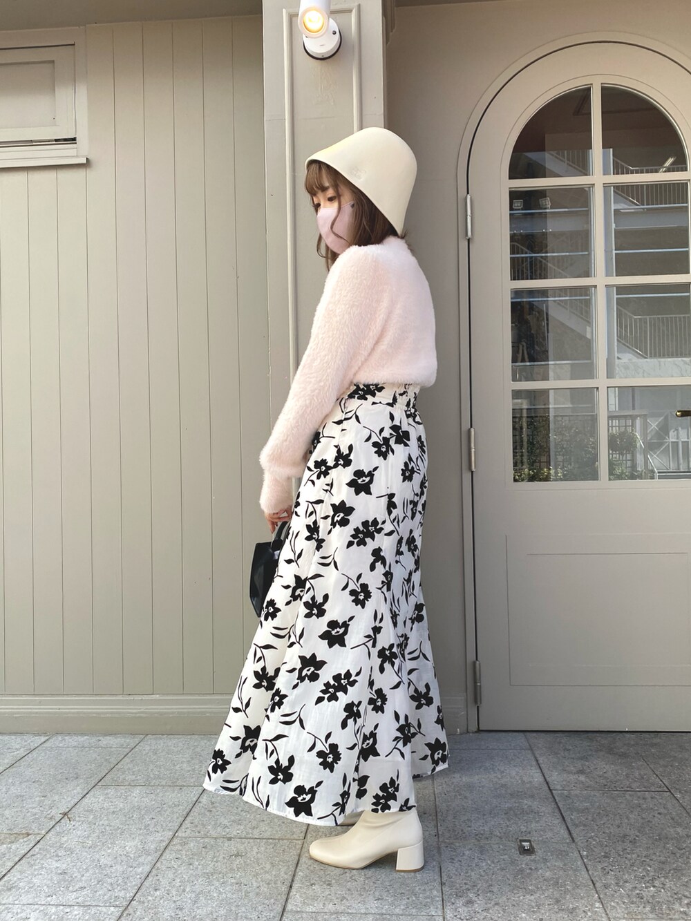 ピンク系のニット/セーター、ホワイト系のスカート、ブラック系のショルダーバッグを着用したレディースの秋コーディネートの2枚目の写真