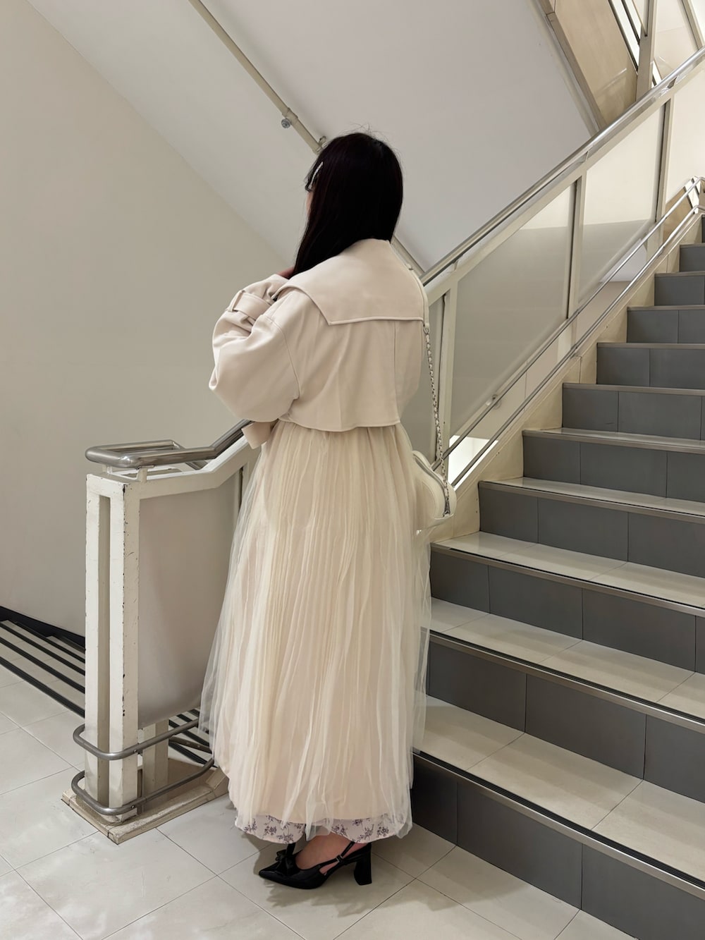 ブラック系のパンプス、ホワイト系のトレンチコート、ホワイト系のショルダーバッグを着用したレディースの春コーディネートの3枚目の写真