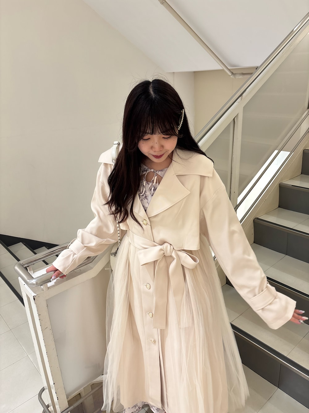 ブラック系のパンプス、ホワイト系のトレンチコート、ホワイト系のショルダーバッグを着用したレディースの春コーディネートの4枚目の写真