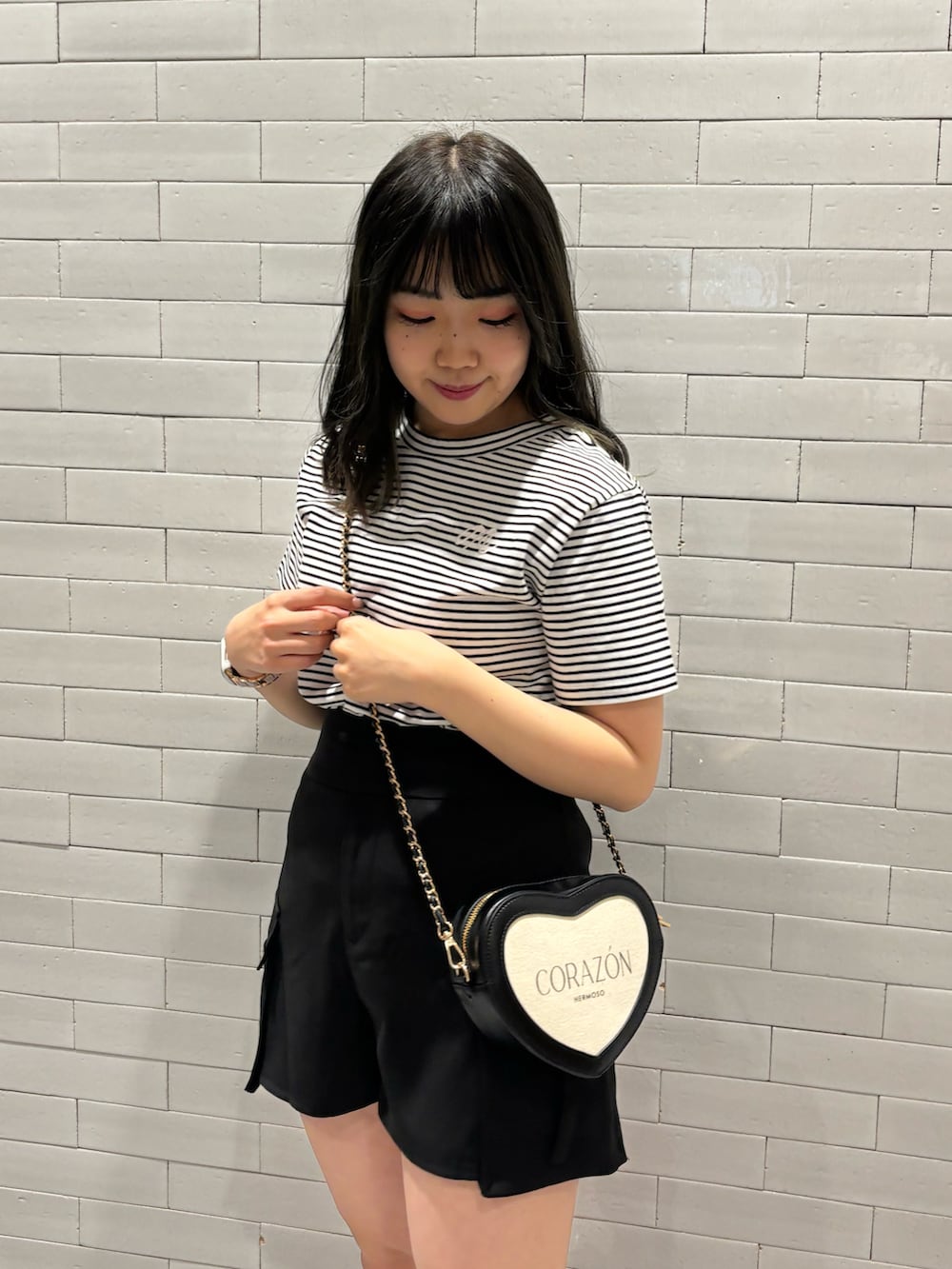 ブラック系のショルダーバッグ、ブラック系のその他パンツ、ホワイト系のTシャツ/カットソーを着用したレディースの春コーディネートの2枚目の写真