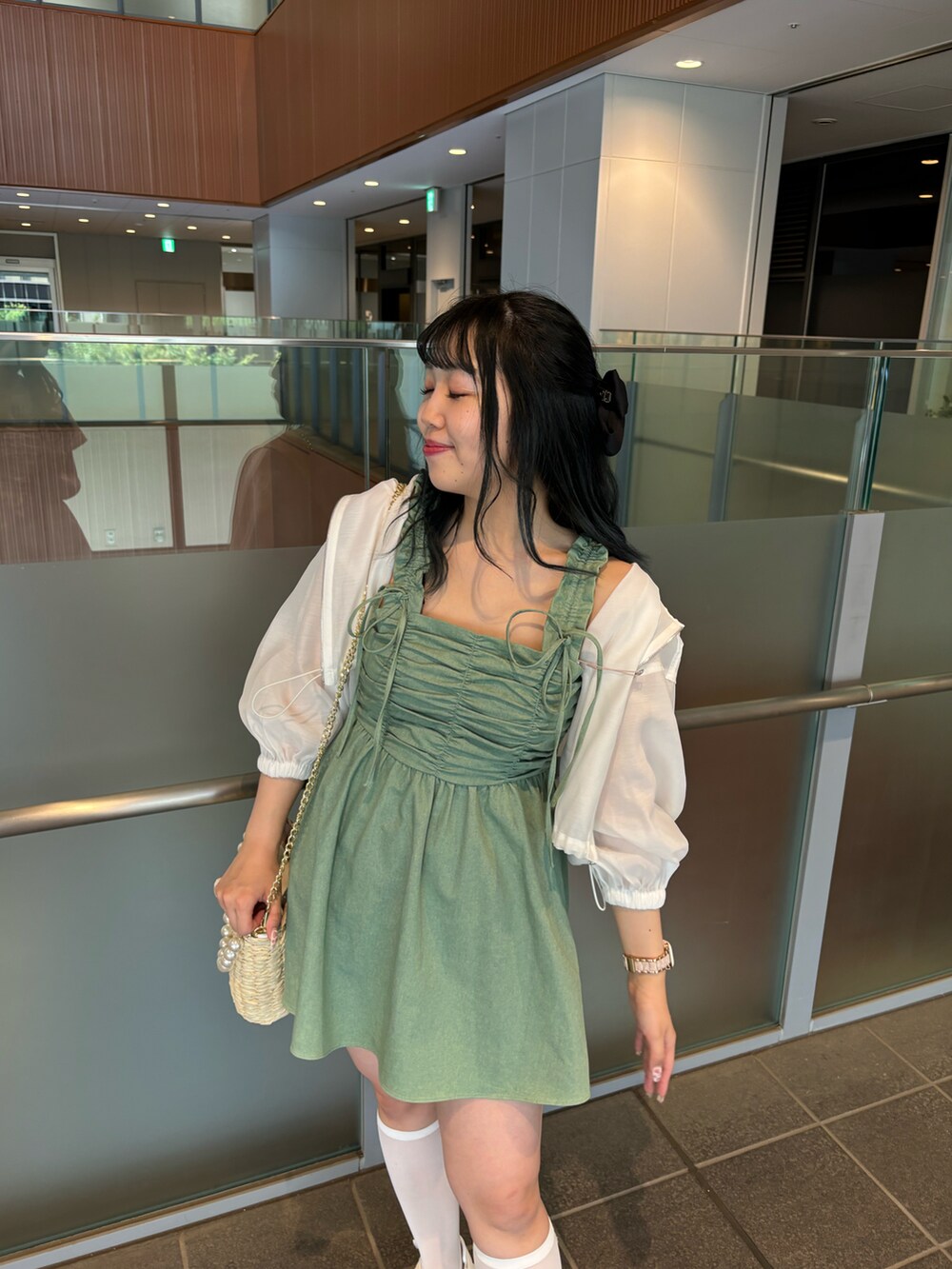 ホワイト系のサンダル、ホワイト系のかごバッグ、グリーン系のキャミソールを着用したレディースの夏コーディネートの2枚目の写真