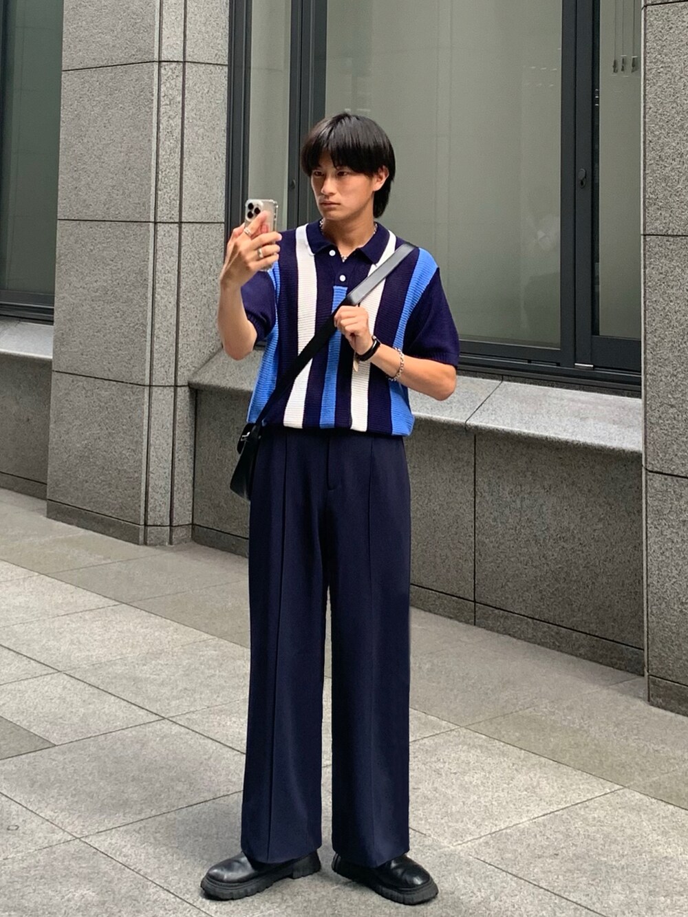 ブルー系のポロシャツ、ブルー系のパンツ、ブラック系のブーツを着用したメンズの夏コーディネートの2枚目の写真