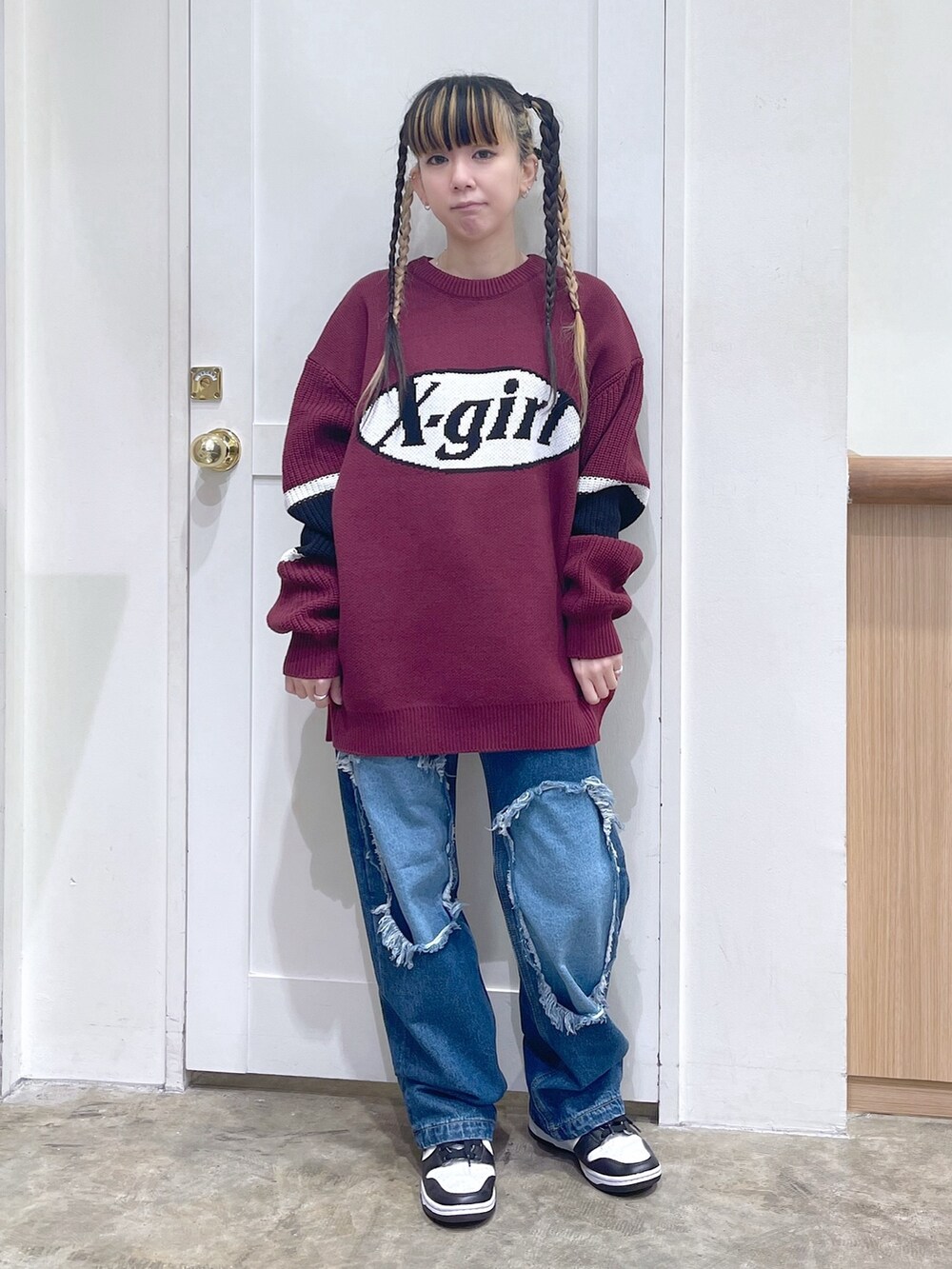 レッド系のニット/セーター、ブルー系のデニムパンツ、ホワイト系のマフラーを着用したレディースの冬コーディネートの2枚目の写真