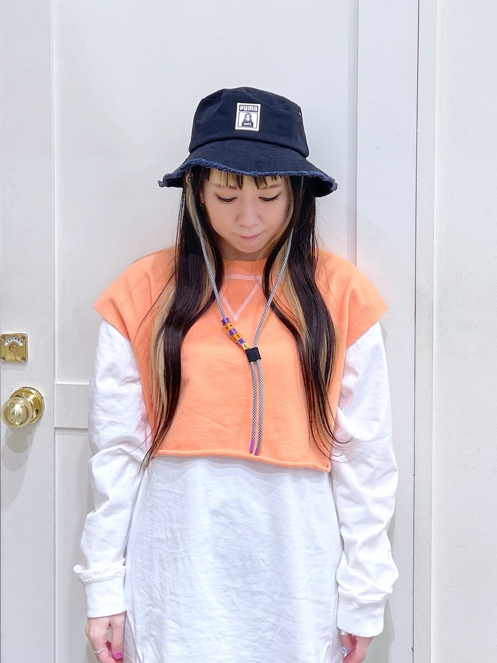 オレンジ系のベスト、ホワイト系のTシャツ/カットソー、ブラック系のスウェットパンツを着用したレディースの春コーディネートの6枚目の写真