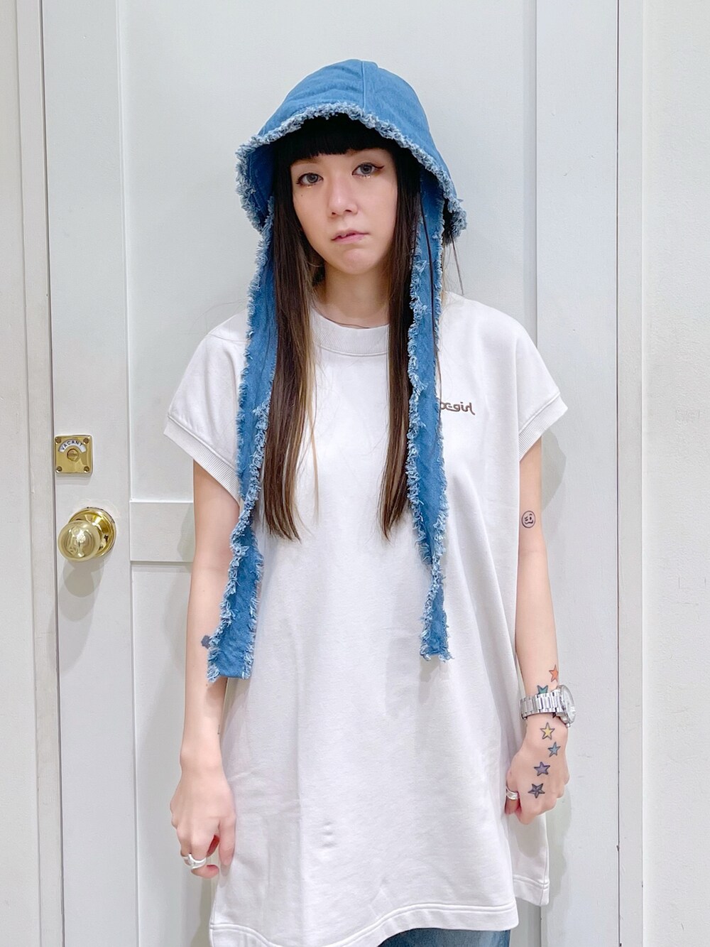 ホワイト系のワンピース、ブルー系のデニムパンツ、ホワイト系のスニーカーを着用したレディースの夏コーディネートの5枚目の写真