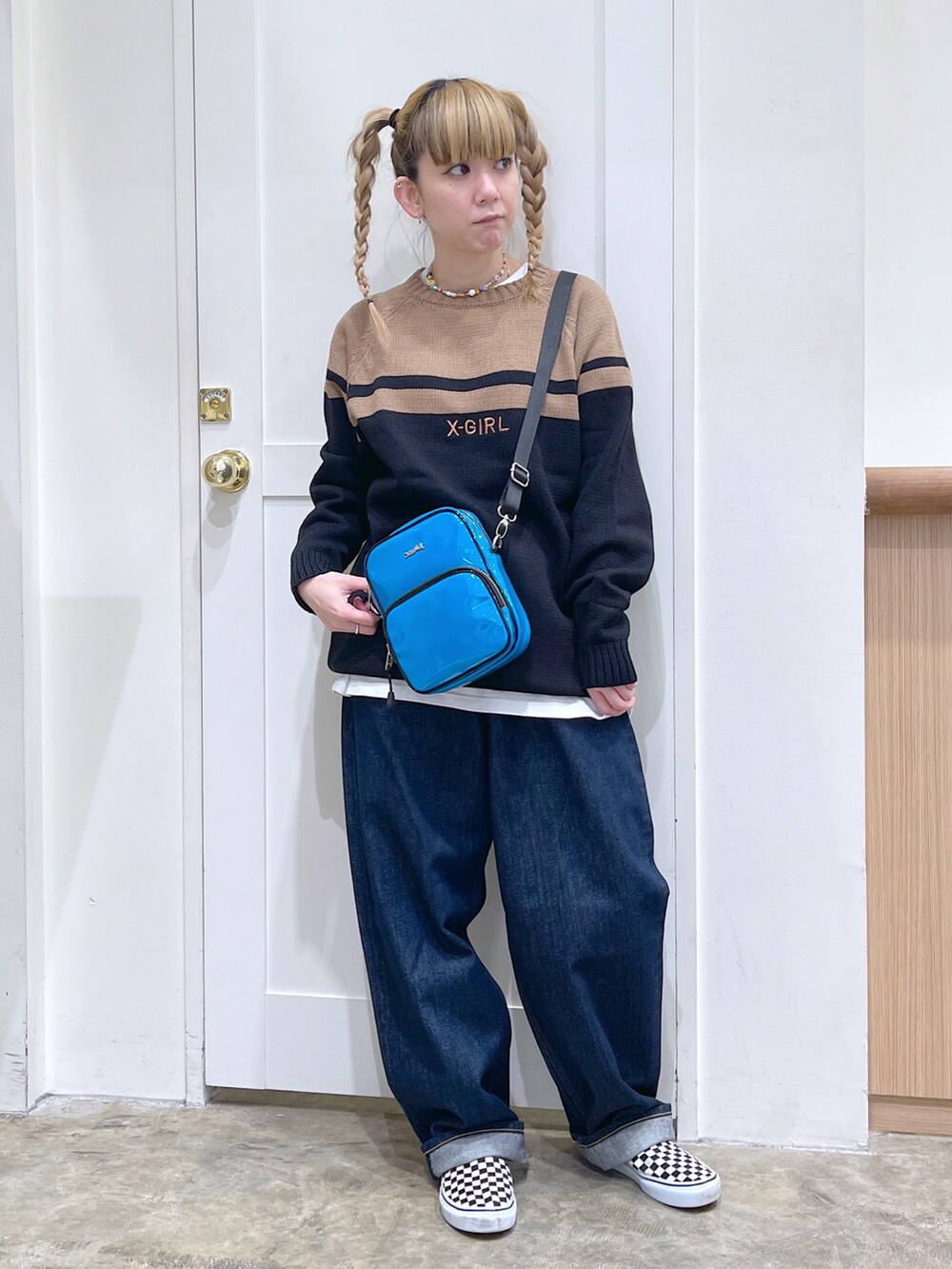 ブラック系のワンピース、ブルー系のデニムパンツ、ブルー系のショルダーバッグを着用したレディースの秋コーディネートの2枚目の写真