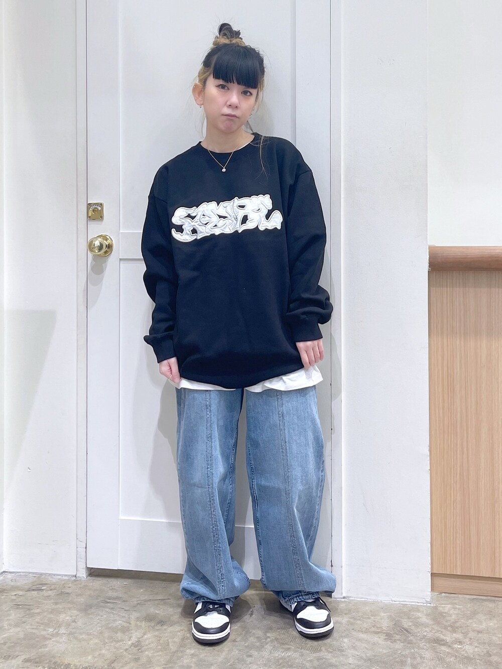 グリーン系のナイロンジャケット、ブラック系のスウェット、ブルー系のデニムパンツを着用したレディースの秋コーディネートの4枚目の写真