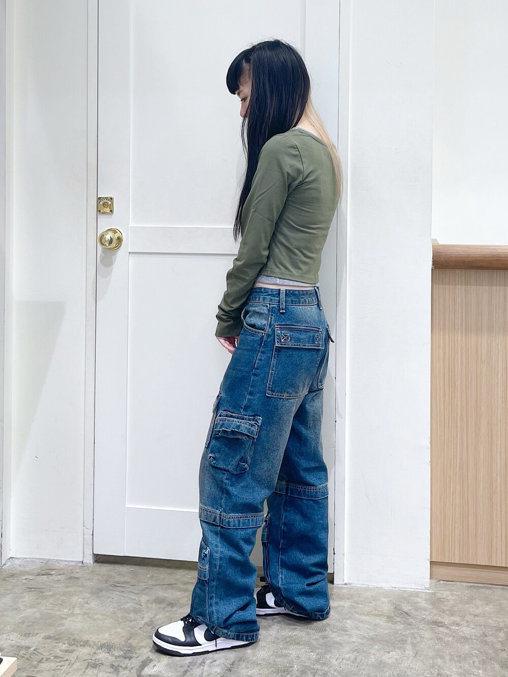 グリーン系のトップス、ブラック系のショルダーバッグ、ブルー系のデニムパンツを着用したレディースの夏コーディネートの2枚目の写真