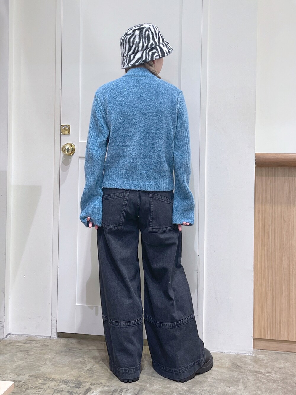 ブルー系のニット/セーター、ブラック系のデニムパンツ、ホワイト系のハットを着用したレディースの秋コーディネートの4枚目の写真