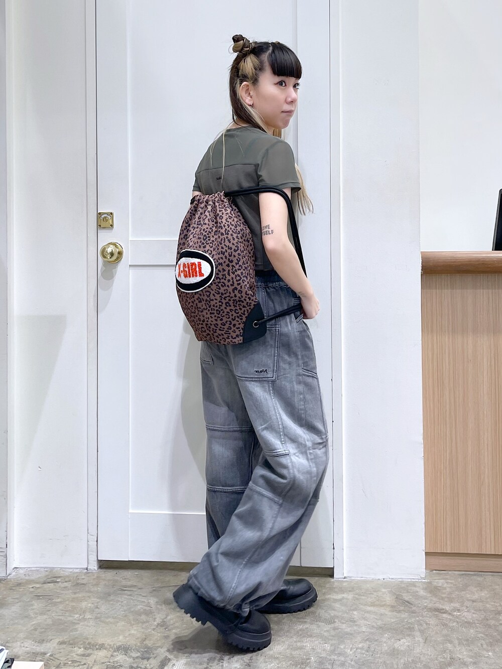 グリーン系のTシャツ/カットソー、ブラック系のデニムパンツ、ブラウン系のバックパック/リュックを着用したレディースの夏コーディネートの3枚目の写真