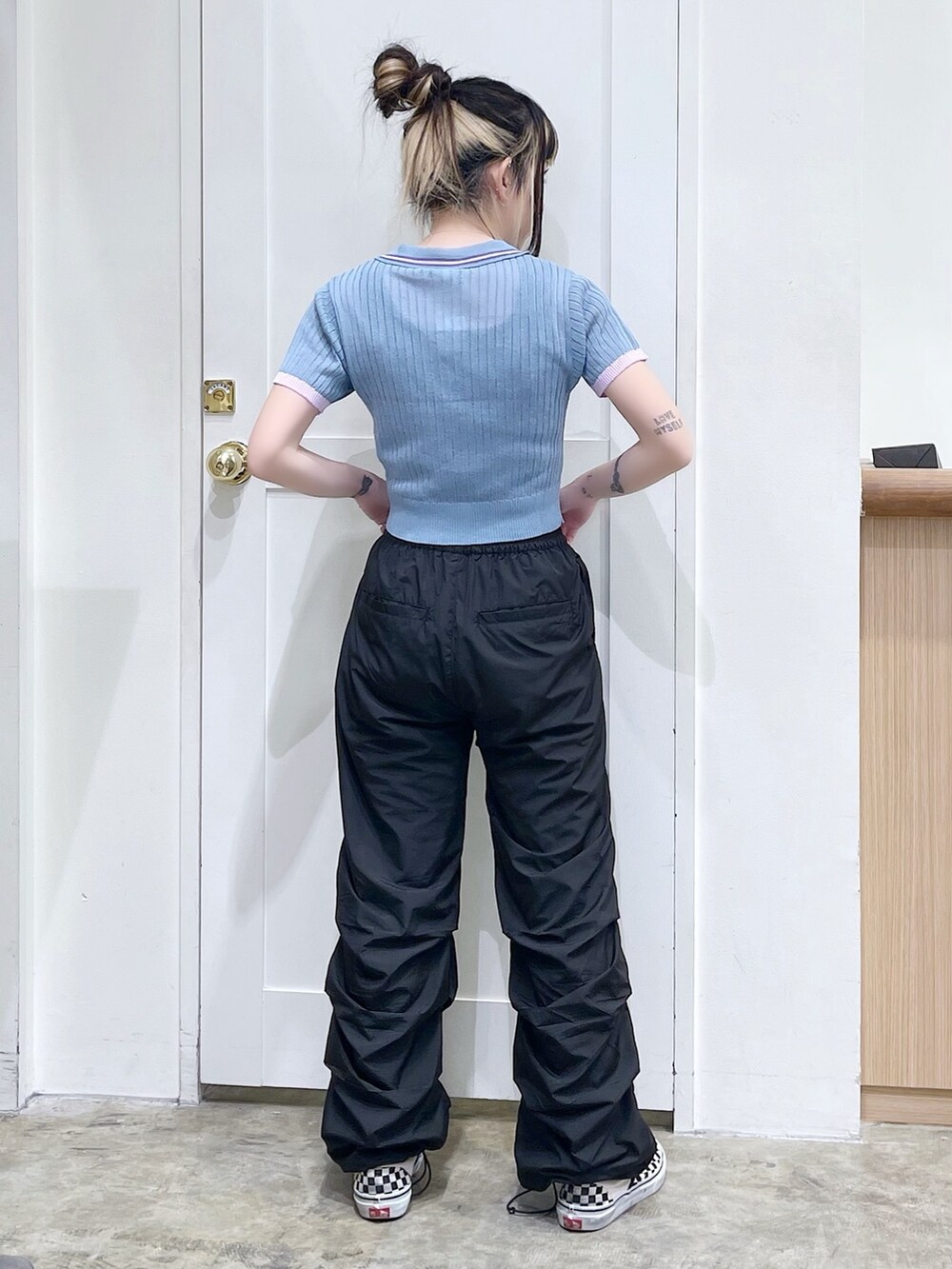 ブルー系のポロシャツ、ブラック系のその他パンツ、ベージュ系のハンドバッグを着用したレディースの春コーディネートの4枚目の写真