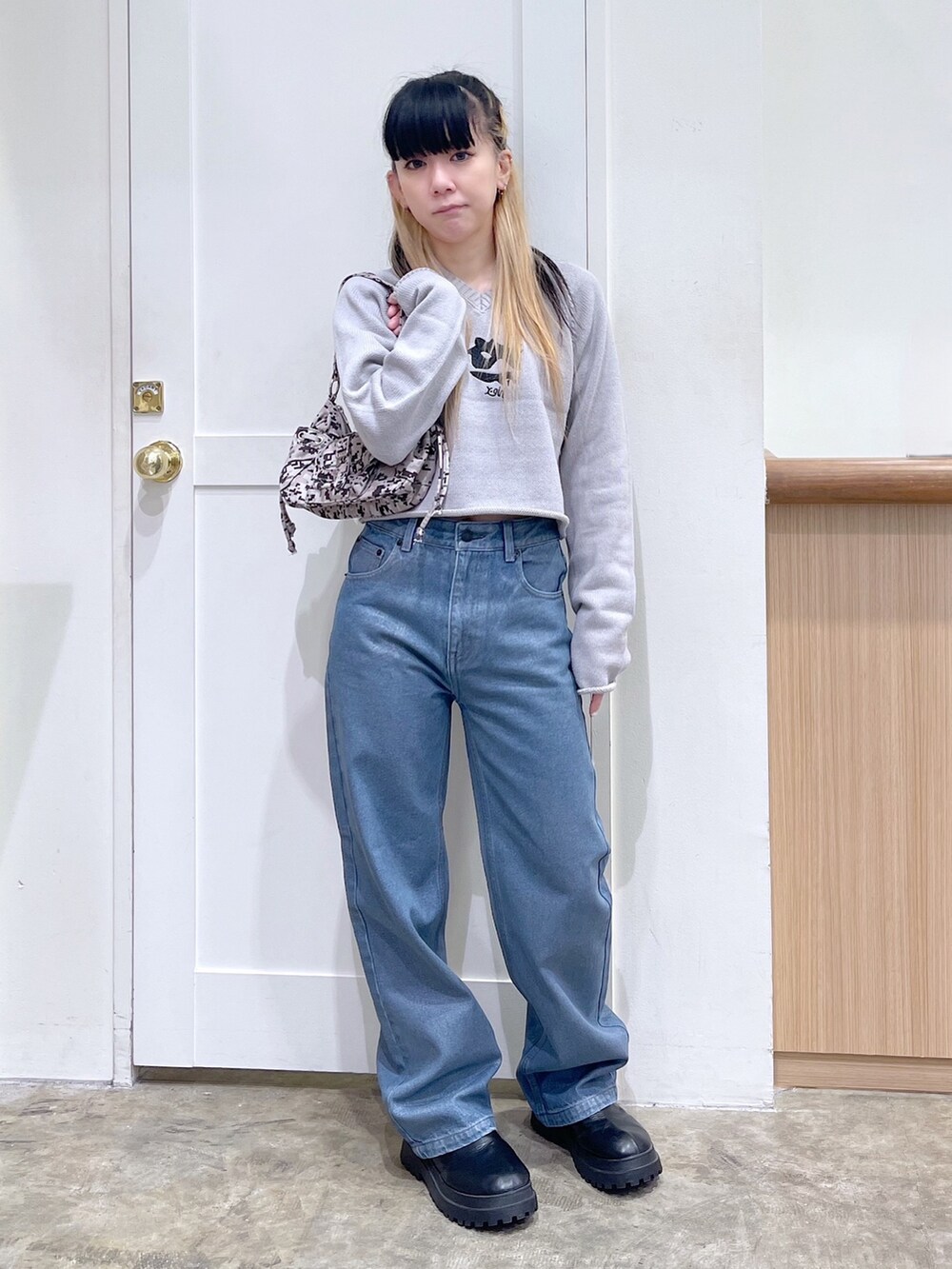 グレー系のニット/セーター、ブルー系のデニムパンツ、ベージュ系のハンドバッグを着用したレディースの秋コーディネートの2枚目の写真