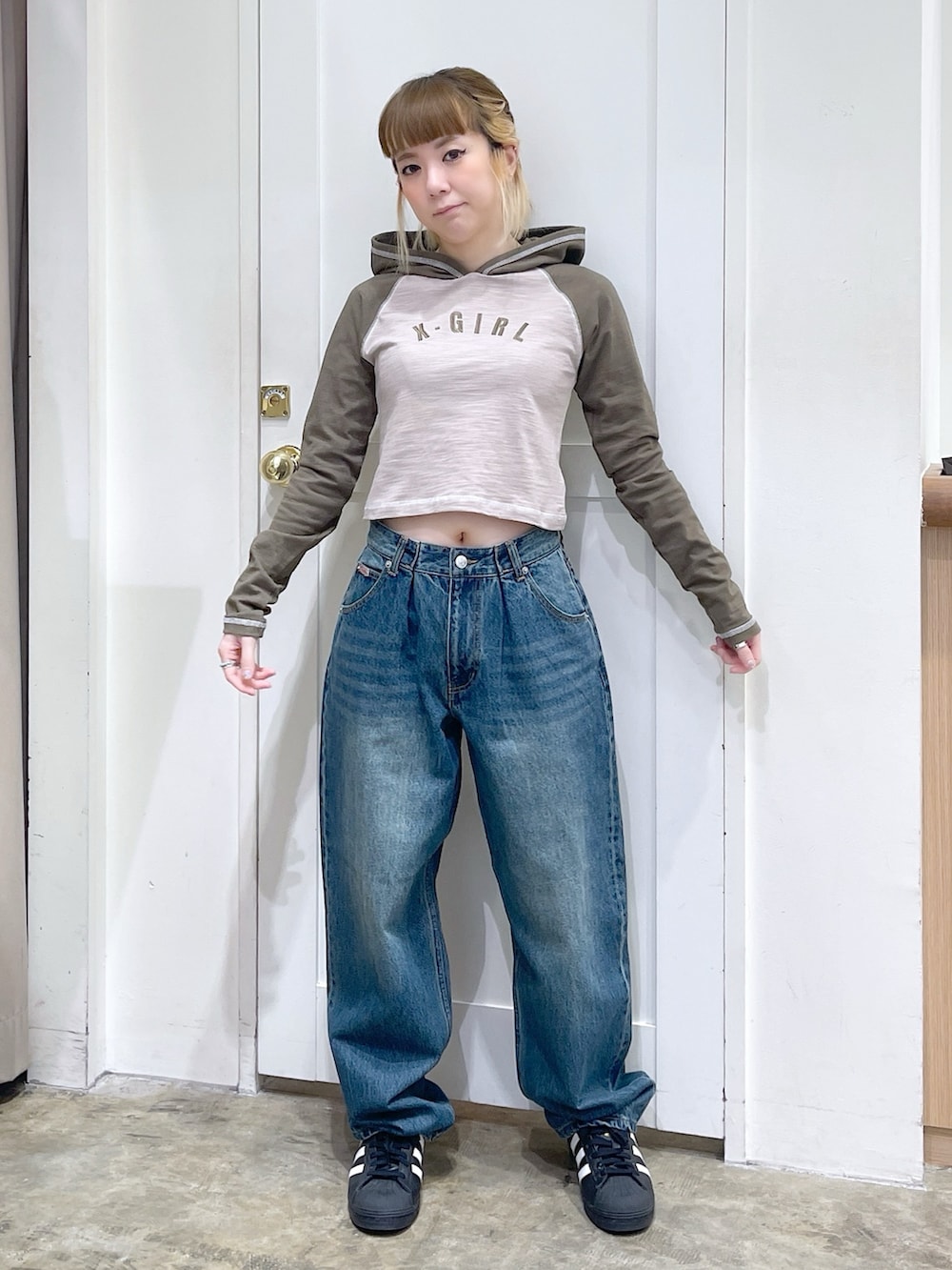 ベージュ系のパーカー、ブルー系のデニムパンツ、ブラック系のショルダーバッグを着用したレディースの春コーディネートの2枚目の写真