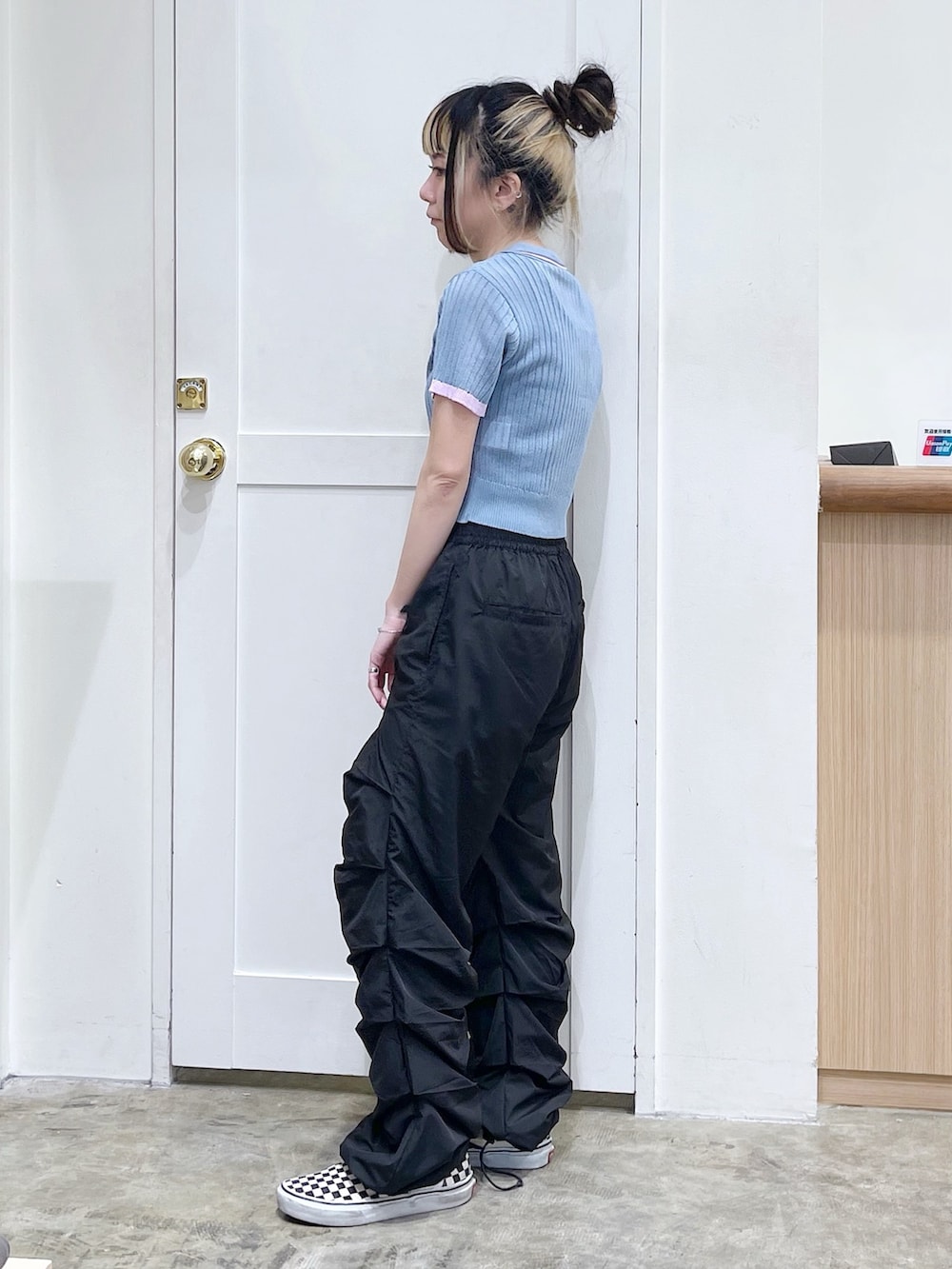 ブルー系のポロシャツ、ブラック系のその他パンツ、ベージュ系のハンドバッグを着用したレディースの春コーディネートの3枚目の写真