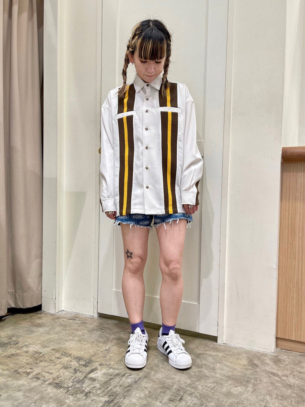 イエロー系のタンクトップ、ホワイト系のシャツ/ブラウス、ブルー系のデニムパンツを着用したレディースの春コーディネートの2枚目の写真