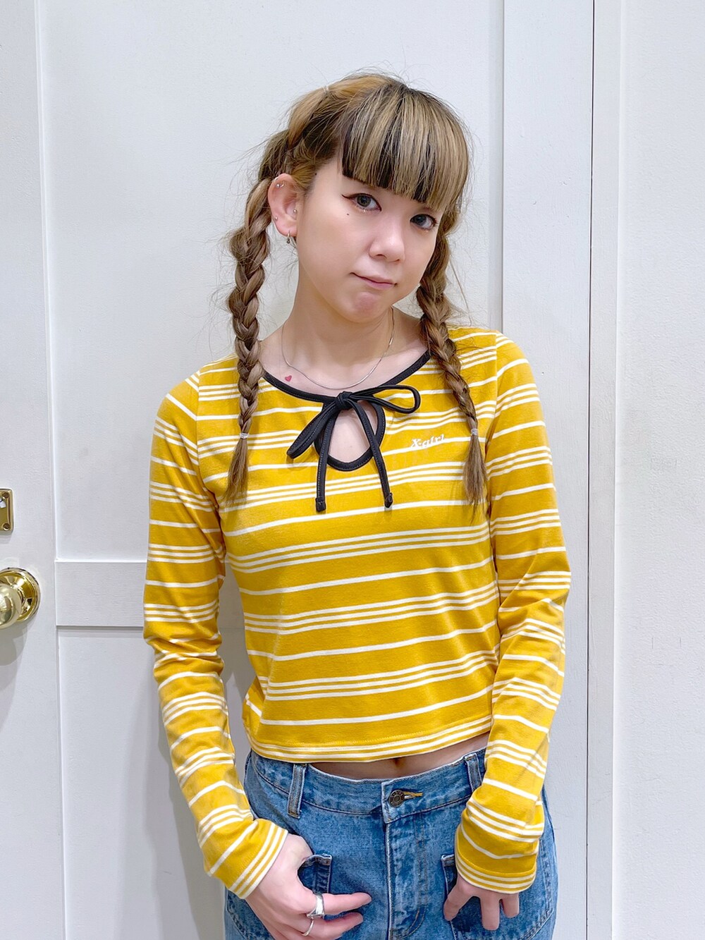 イエロー系のTシャツ/カットソー、ホワイト系のハンドバッグ、ブルー系のデニムパンツを着用したレディースの春コーディネートの3枚目の写真