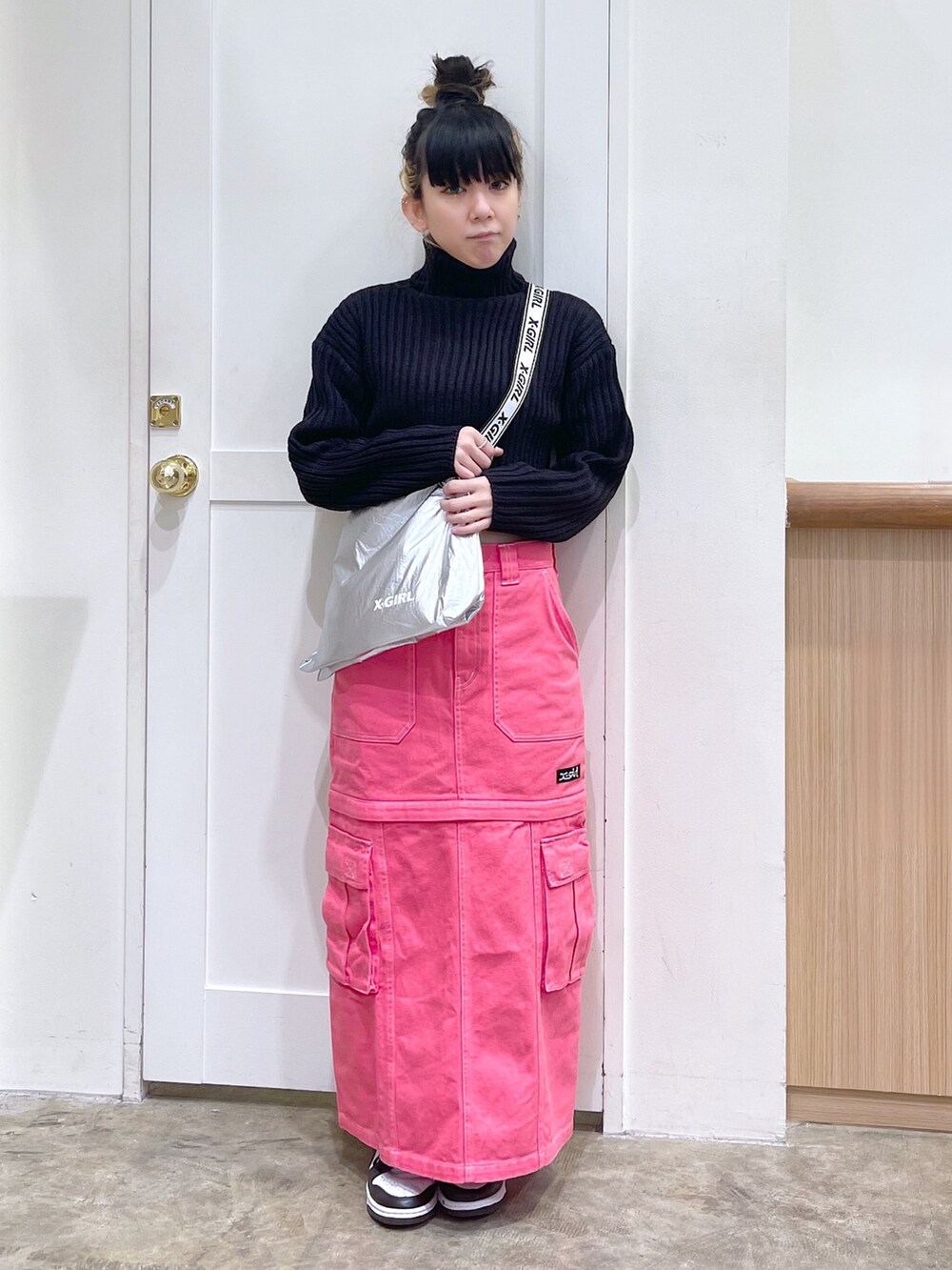 ブラック系のニット/セーター、シルバー系のショルダーバッグ、ピンク系のスカートを着用したレディースの秋コーディネートの2枚目の写真