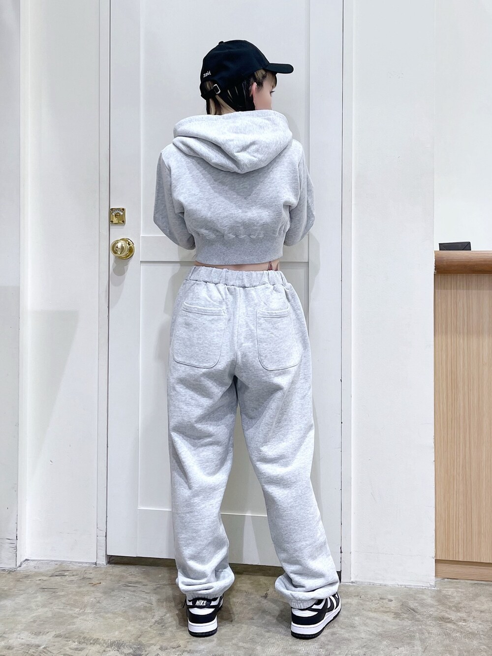 グレー系のパーカー、グレー系のスウェットパンツ、ブラック系のキャップを着用したレディースの春コーディネートの3枚目の写真