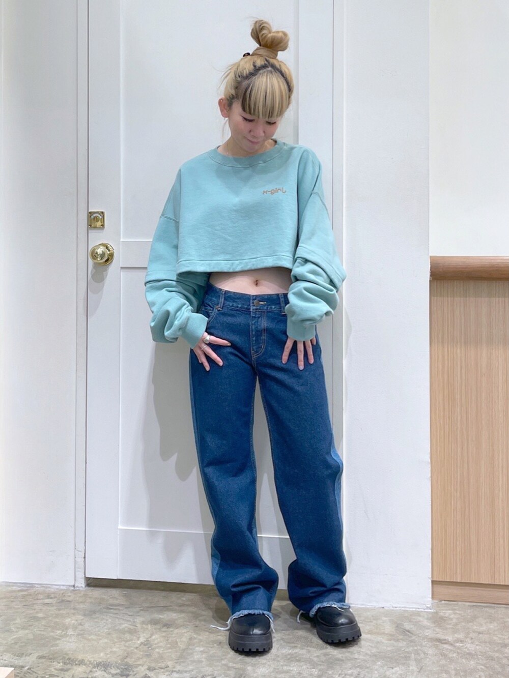 グリーン系のワンピース、ブルー系のデニムパンツ、ブラック系のショルダーバッグを着用したレディースの冬コーディネートの3枚目の写真