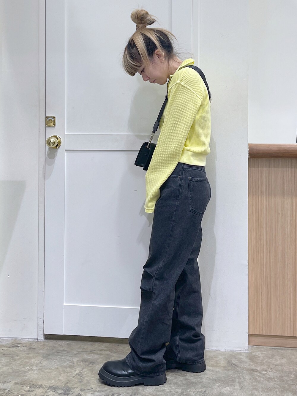 イエロー系のTシャツ/カットソー、ブラック系のショルダーバッグ、ブラック系のデニムパンツを着用したレディースの秋コーディネートの2枚目の写真