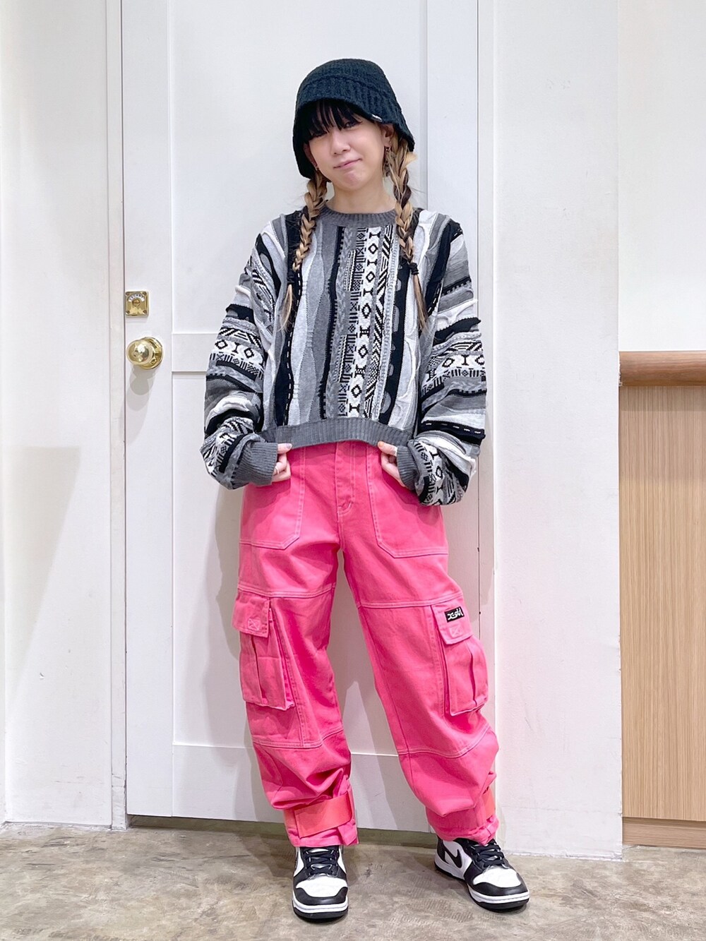 ブラック系のニット/セーター、ブラック系のメッセンジャーバッグ、ピンク系のカーゴパンツを着用したレディースの秋コーディネートの2枚目の写真