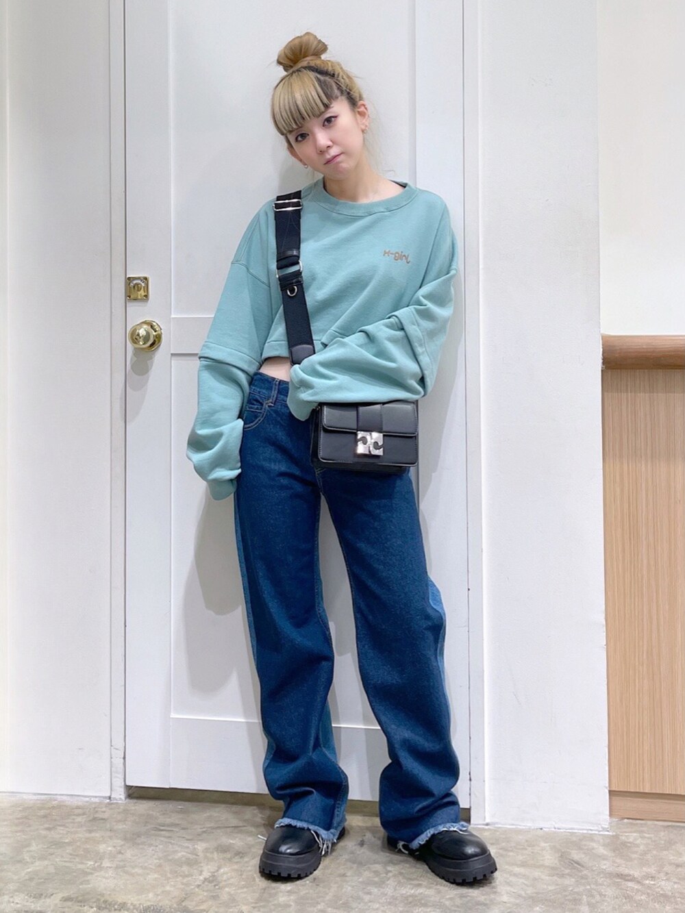 グリーン系のワンピース、ブルー系のデニムパンツ、ブラック系のショルダーバッグを着用したレディースの冬コーディネートの2枚目の写真