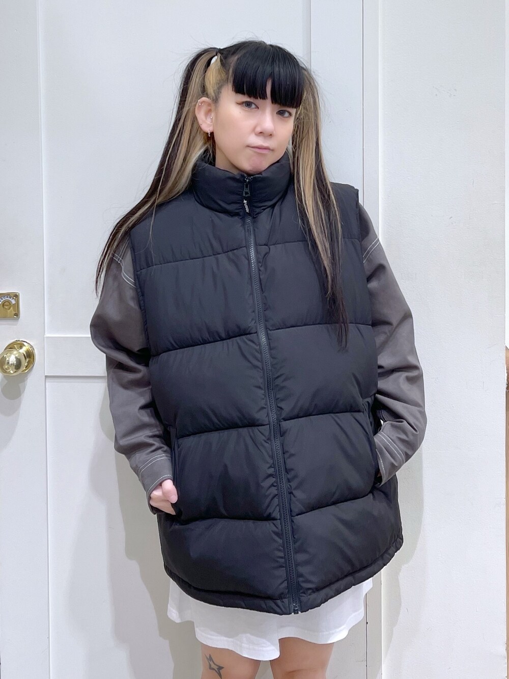 ブラック系のダウンベスト、グリーン系のシャツ/ブラウス、ホワイト系のワンピースを着用したレディースの秋コーディネートの2枚目の写真