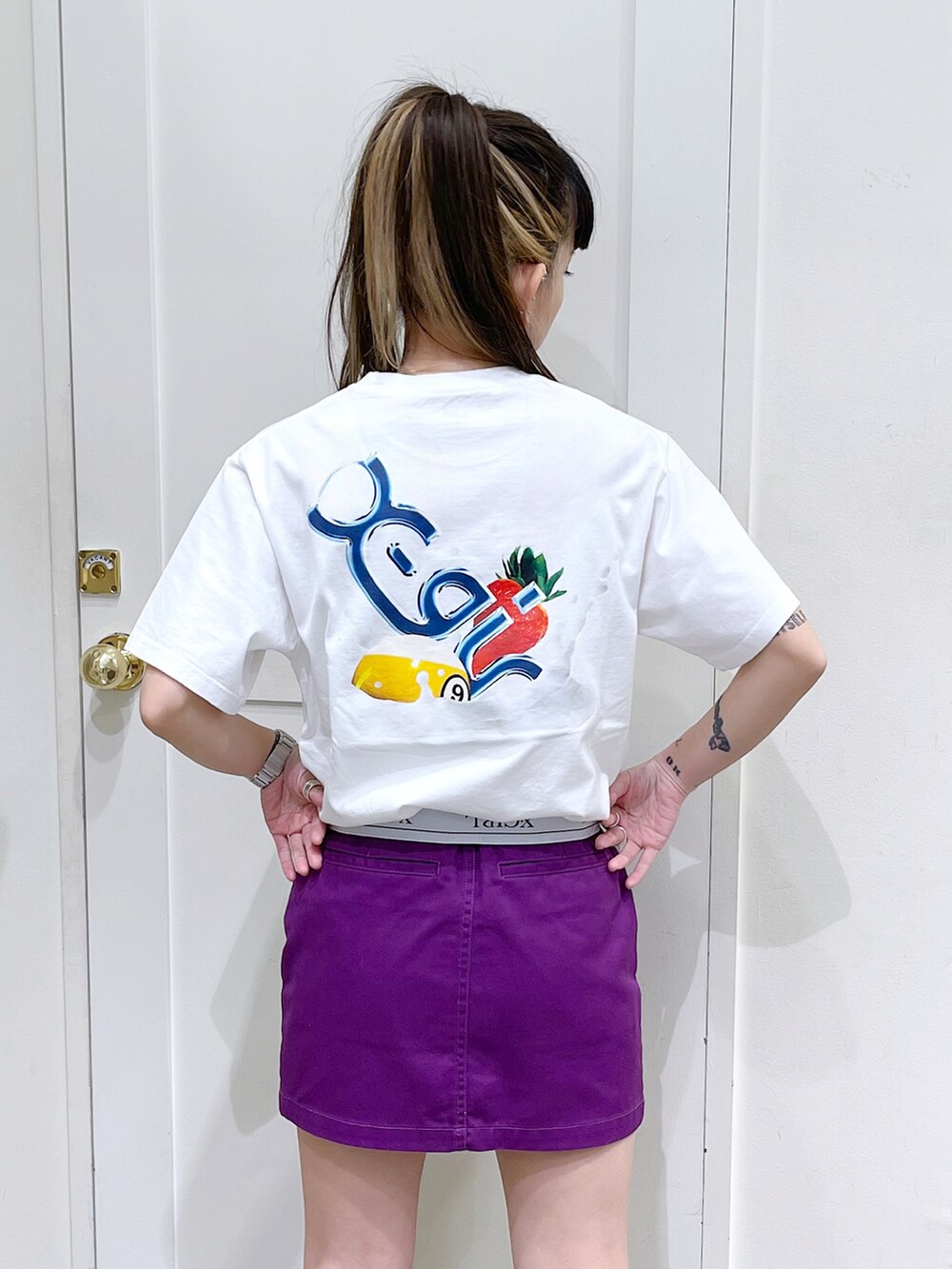 ホワイト系のTシャツ/カットソー、パープル系のスカート、ブラック系のトートバッグを着用したレディースの夏コーディネートの5枚目の写真