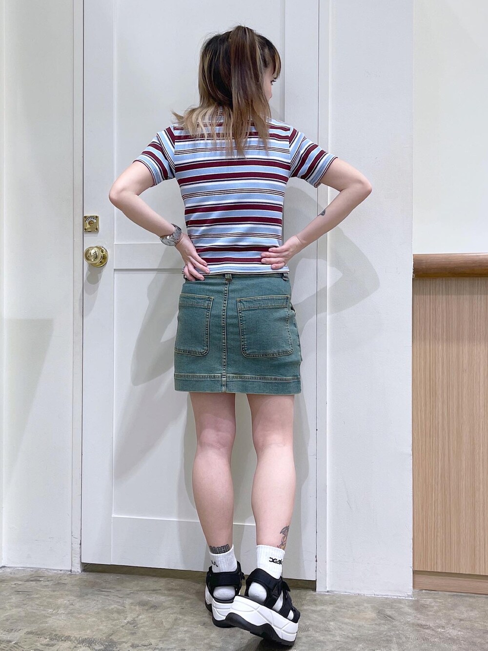 レッド系のTシャツ/カットソー、ブルー系のスカート、ブラック系のサンダルを着用したレディースの夏コーディネートの3枚目の写真