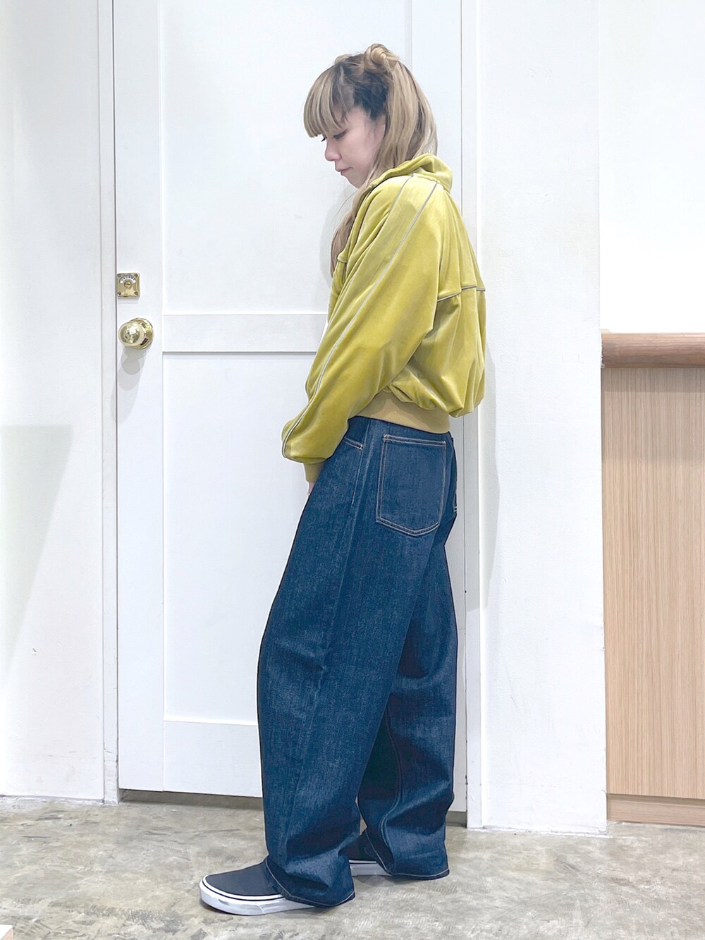 イエロー系のスウェット、ホワイト系のTシャツ/カットソー、ブルー系のデニムパンツを着用したレディースの秋コーディネートの2枚目の写真