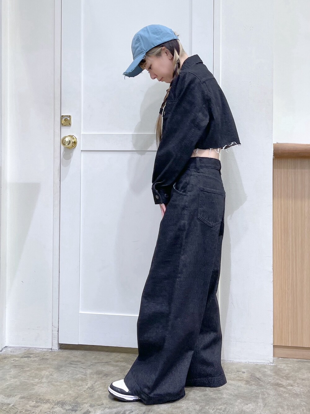 ブラック系のデニムジャケット、ブラック系のデニムパンツ、ブルー系のキャップを着用したレディースの冬コーディネートの3枚目の写真