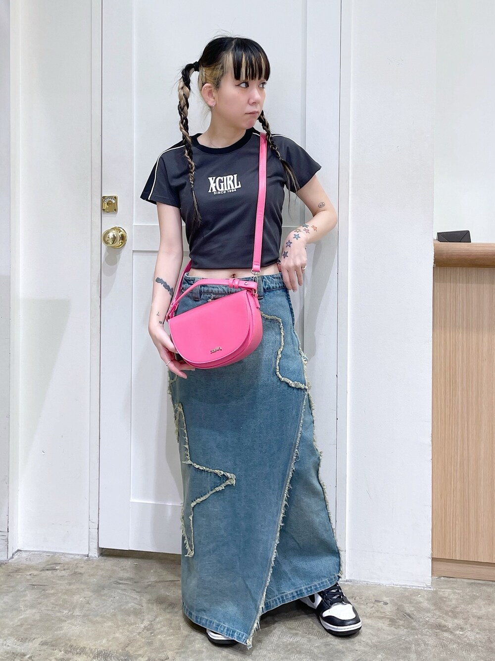 グレー系のTシャツ/カットソー、ブルー系のデニムスカート、ピンク系のショルダーバッグを着用したレディースの春コーディネートの2枚目の写真