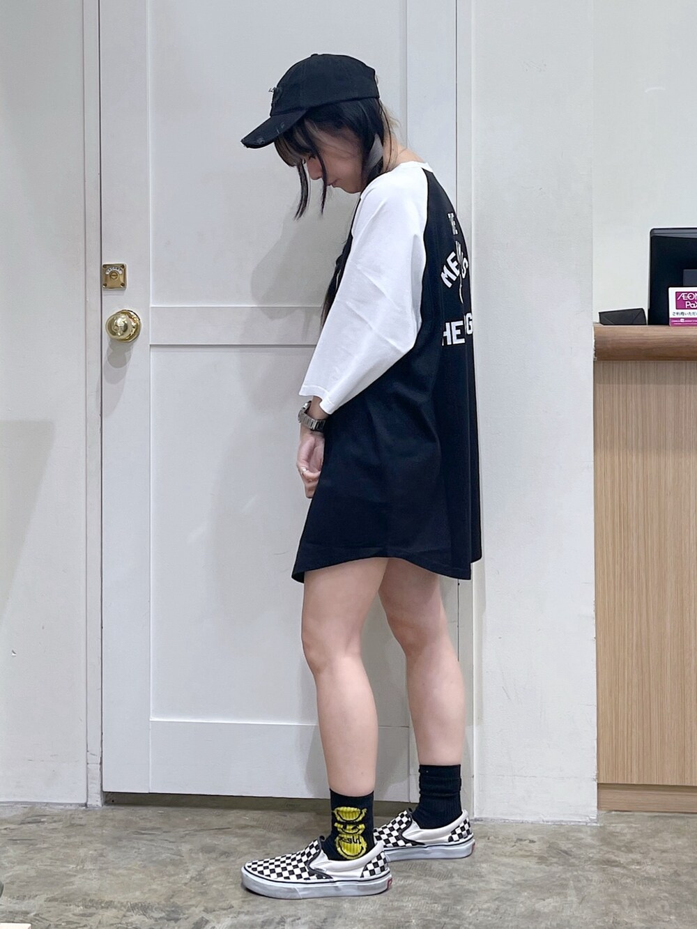 ブラック系のワンピース、その他のトートバッグ、グレー系のキャップを着用したレディースの夏コーディネートの3枚目の写真