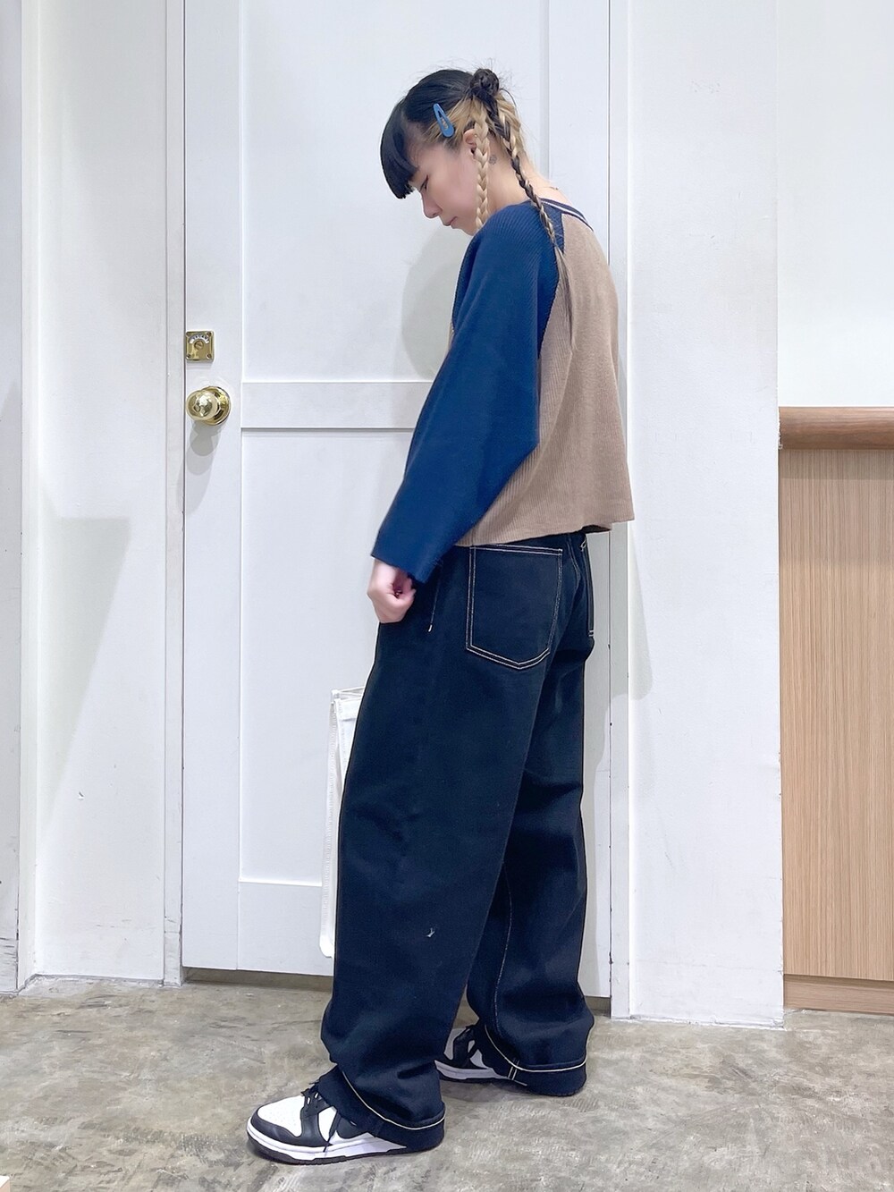 ブルー系のニット/セーター、ブラック系のデニムパンツ、ホワイト系のトートバッグを着用したレディースの秋コーディネートの3枚目の写真