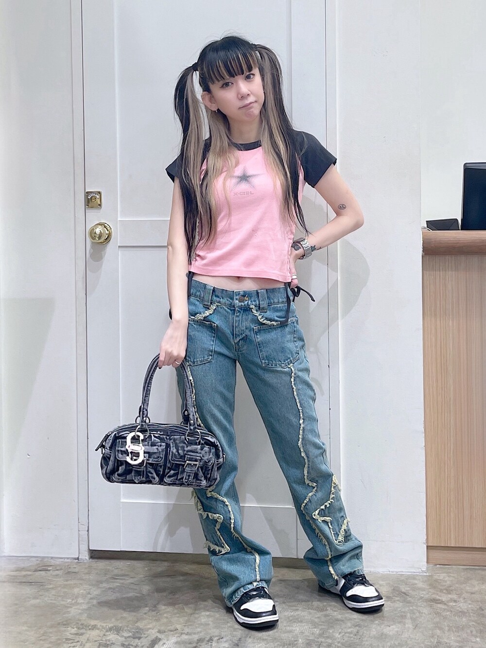 ピンク系のTシャツ/カットソー、ブルー系のデニムパンツ、ブラック系のハンドバッグを着用したレディースの夏コーディネートの2枚目の写真