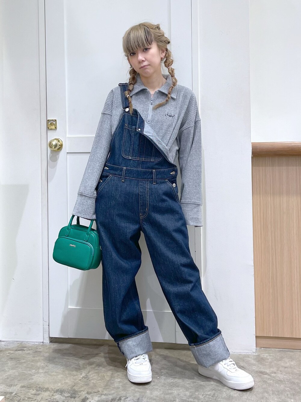 グレー系のスウェット、ブルー系のサロペット/オーバーオール、グリーン系のショルダーバッグを着用したレディースの冬コーディネートの3枚目の写真