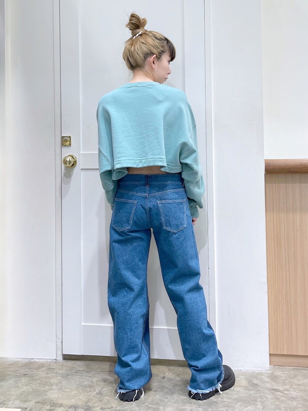 グリーン系のワンピース、ブルー系のデニムパンツ、ブラック系のショルダーバッグを着用したレディースの冬コーディネートの5枚目の写真