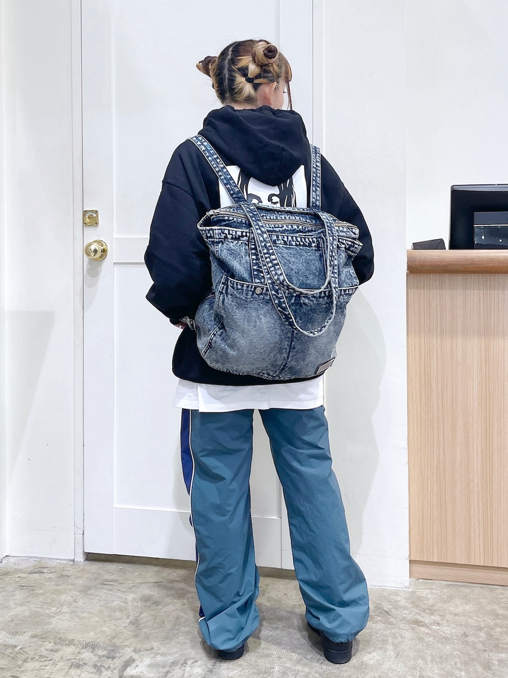 ブラック系のパーカー、グリーン系のその他パンツ、ブルー系のトートバッグを着用したレディースの秋コーディネートの2枚目の写真