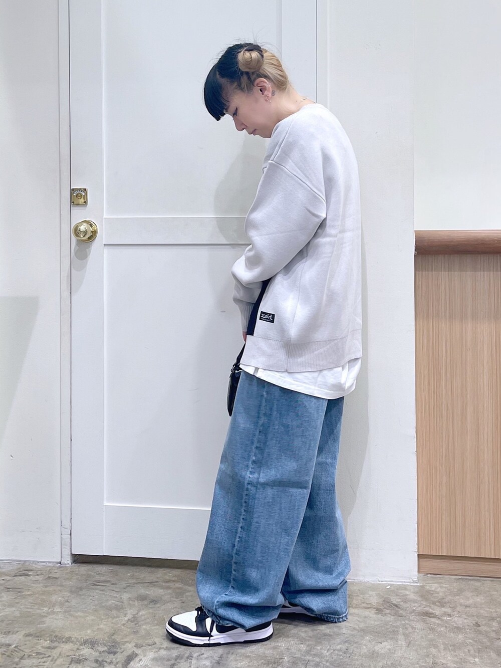 ホワイト系のニット/セーター、ブラック系のショルダーバッグ、ブルー系のデニムパンツを着用したレディースの秋コーディネートの2枚目の写真