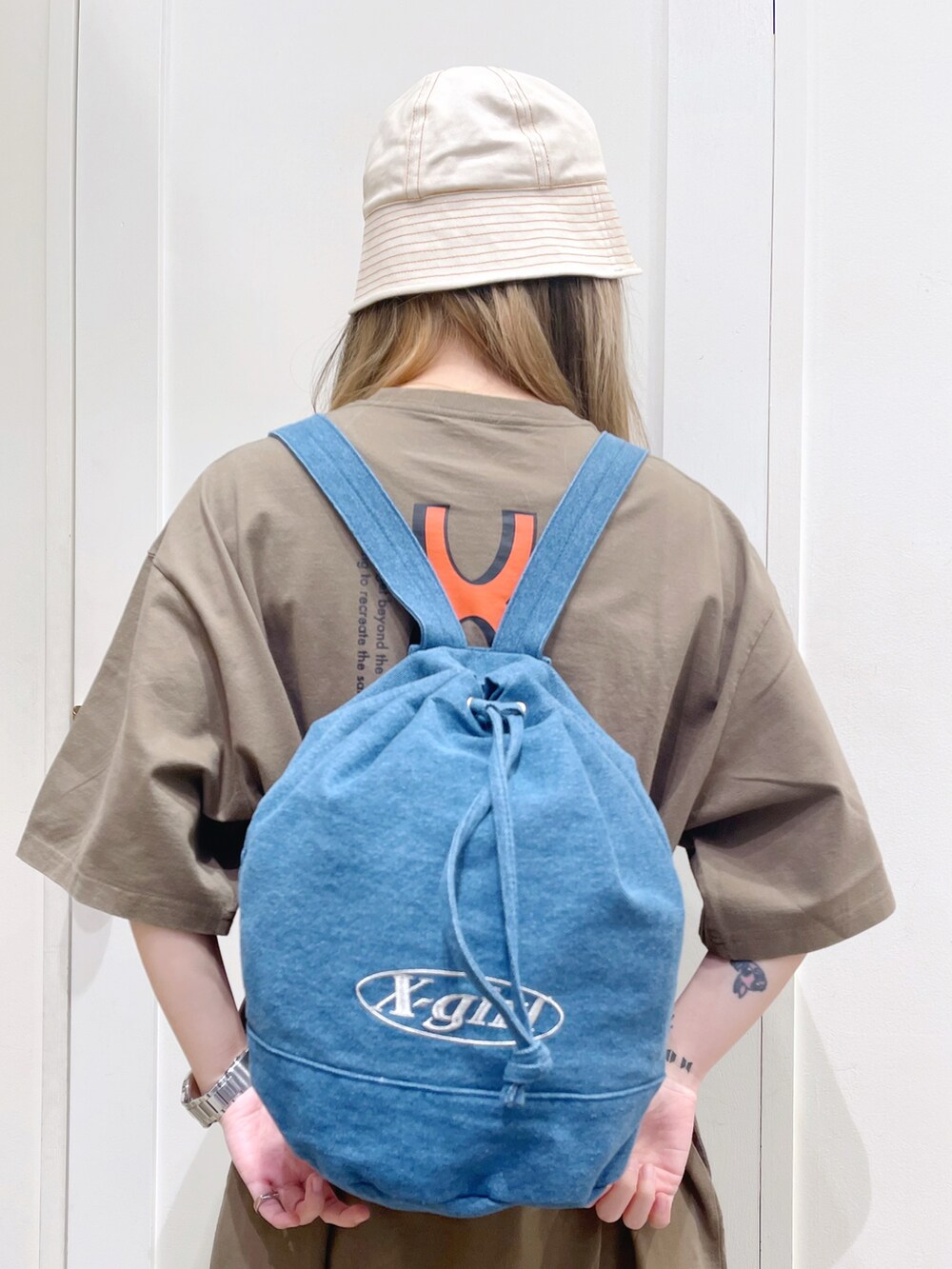 グリーン系のワンピース、ブルー系のバックパック/リュック、ベージュ系のハットを着用したレディースの春コーディネートの5枚目の写真