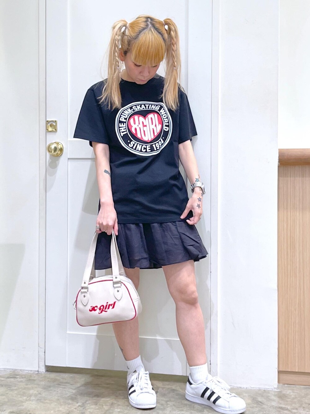 ブラック系のTシャツ/カットソー、ブラック系のスカート、ホワイト系のボストンバッグを着用したレディースの夏コーディネートの2枚目の写真