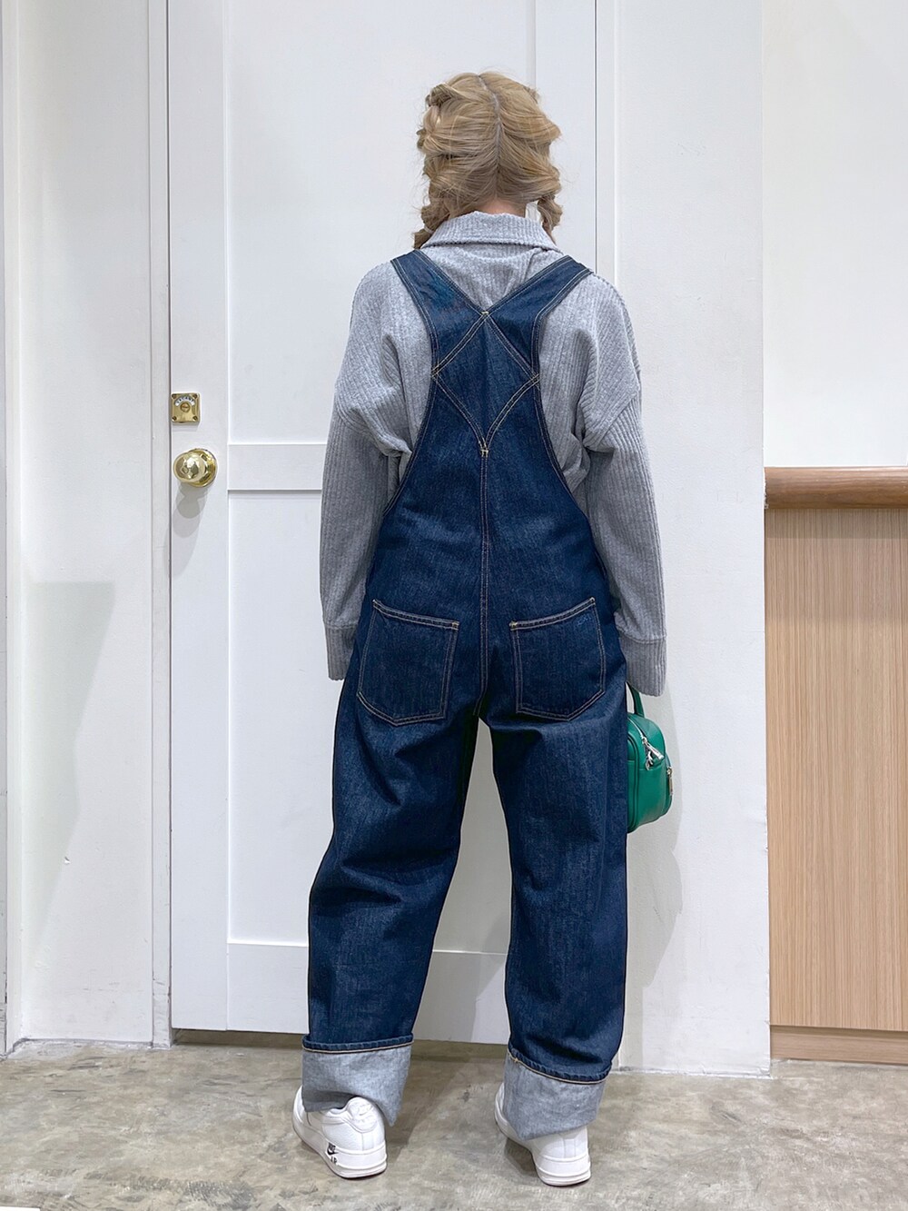 グレー系のスウェット、ブルー系のサロペット/オーバーオール、グリーン系のショルダーバッグを着用したレディースの冬コーディネートの5枚目の写真