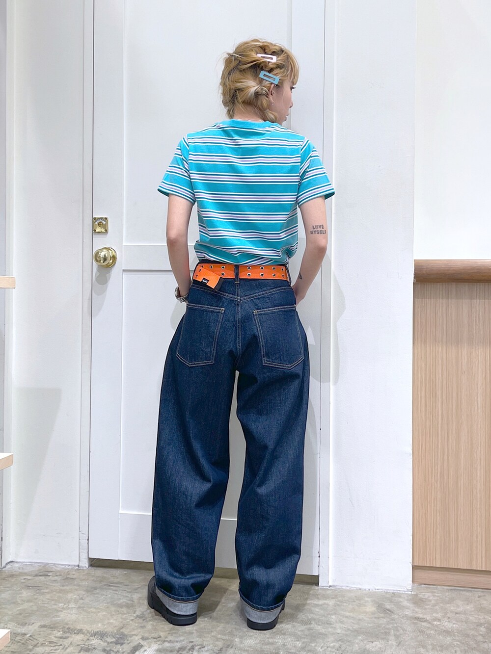 グリーン系のTシャツ/カットソー、ブルー系のデニムパンツ、オレンジ系のベルトを着用したレディースの夏コーディネートの4枚目の写真