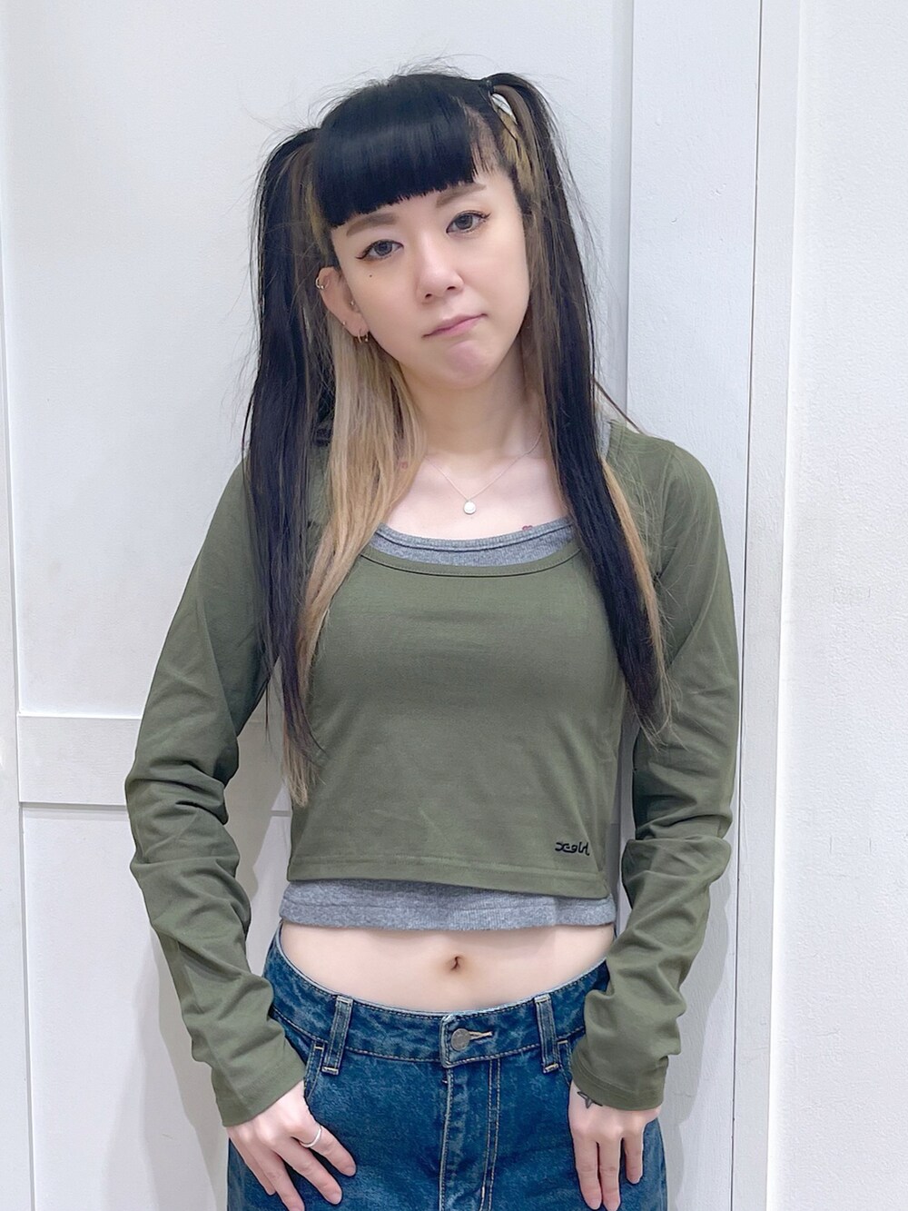 グリーン系のトップス、ブラック系のショルダーバッグ、ブルー系のデニムパンツを着用したレディースの夏コーディネートの4枚目の写真