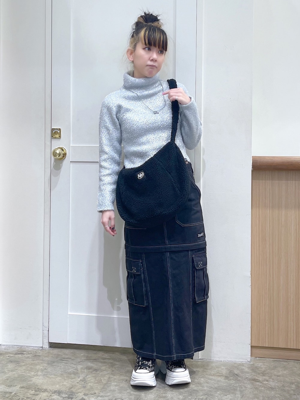 グレー系のニット/セーター、ブラック系のショルダーバッグ、ブラック系のスカートを着用したレディースの秋コーディネートの2枚目の写真