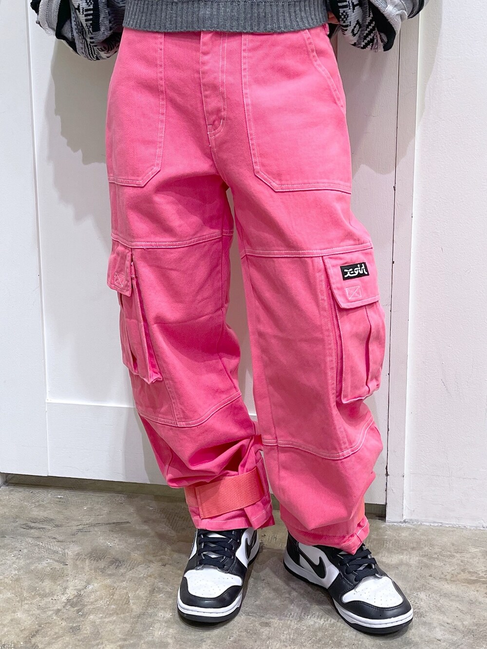 ブラック系のニット/セーター、ブラック系のメッセンジャーバッグ、ピンク系のカーゴパンツを着用したレディースの秋コーディネートの5枚目の写真