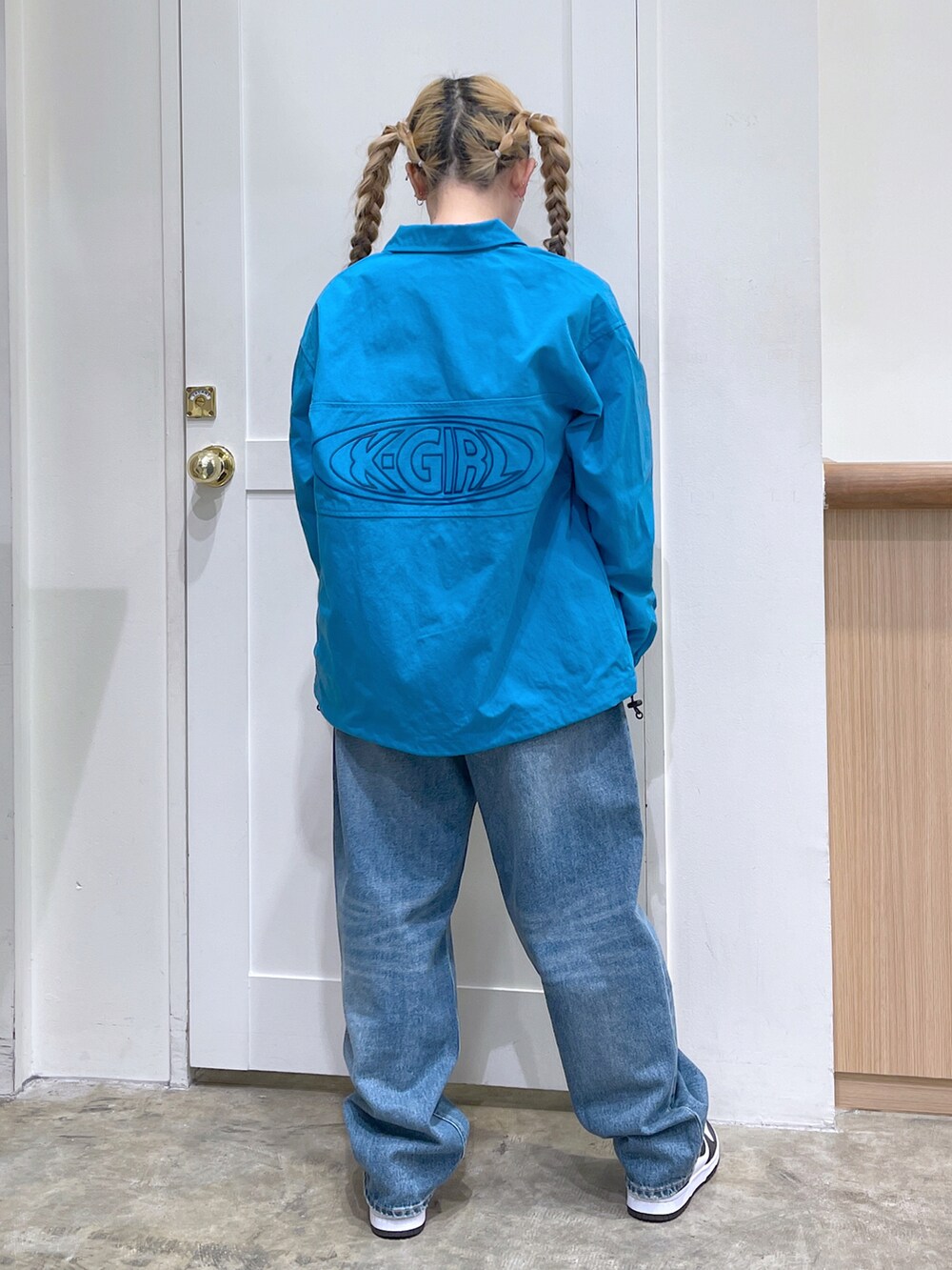 ブルー系のナイロンジャケット、ブラック系のTシャツ/カットソー、ブルー系のデニムパンツを着用したレディースの春コーディネートの2枚目の写真