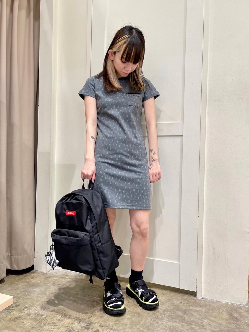 グレー系のワンピース、ブラック系のサンダル、レッド系のバックパック/リュックを着用したレディースの春コーディネートの2枚目の写真