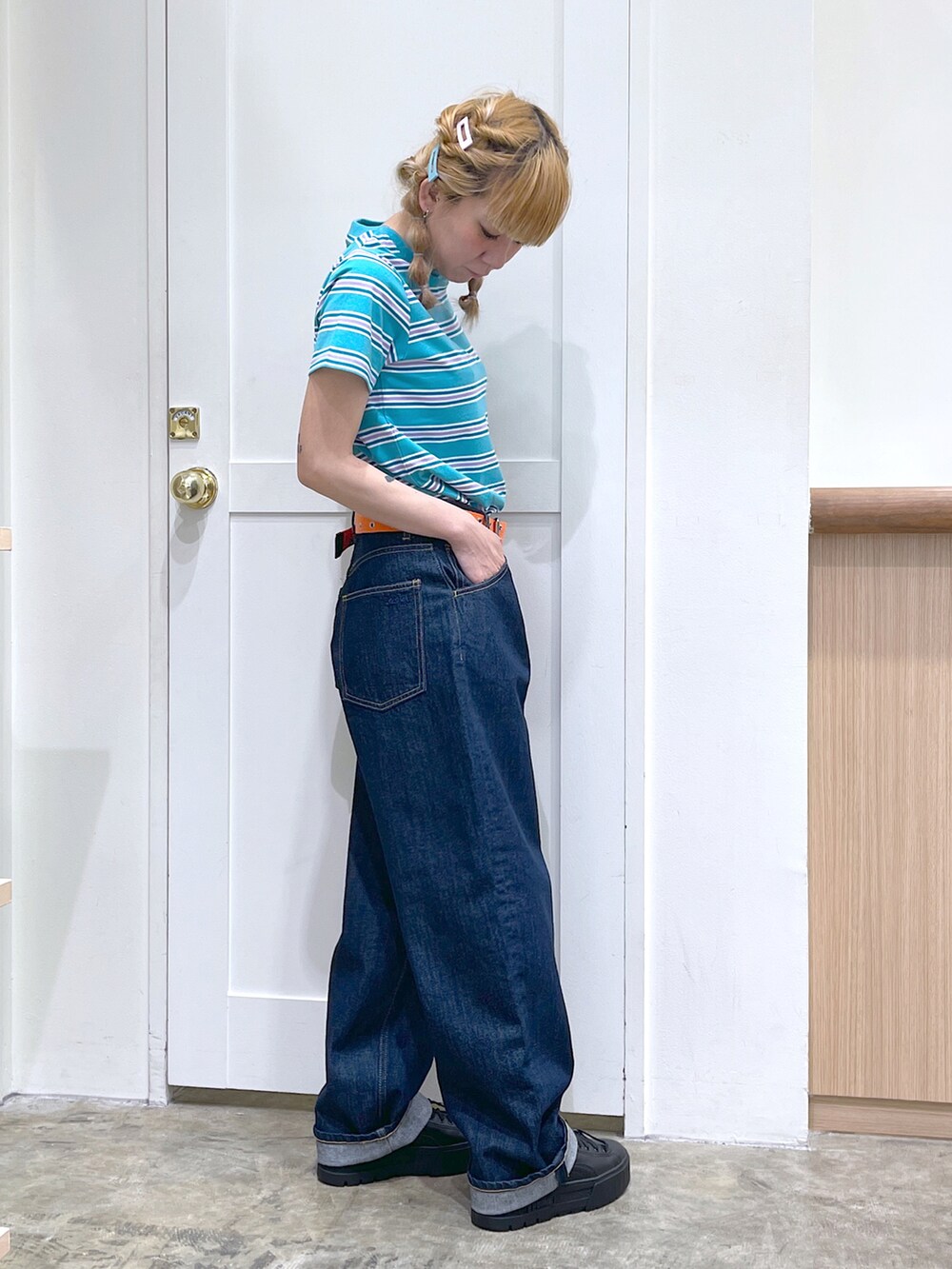 グリーン系のTシャツ/カットソー、ブルー系のデニムパンツ、オレンジ系のベルトを着用したレディースの夏コーディネートの2枚目の写真