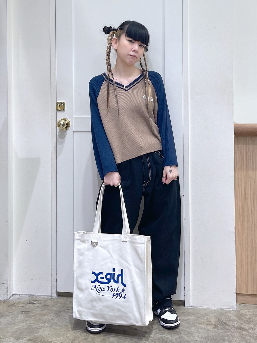 ブルー系のニット/セーター、ブラック系のデニムパンツ、ホワイト系のトートバッグを着用したレディースの秋コーディネートの2枚目の写真